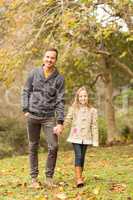 Happy father and daughter walking together in park