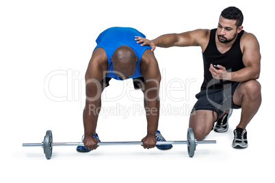 Man lifting barbell with trainer