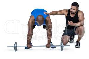 Man lifting barbell with trainer