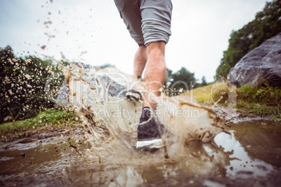 Man jogging through muddy puddles