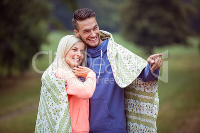 Happy couple hugging under blanket