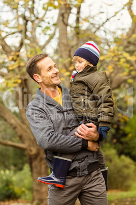 Young dad lifting his little son in park