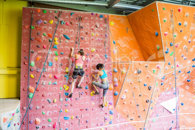 Fit women rock climbing indoors