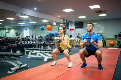 Man and woman working out using kettle bells