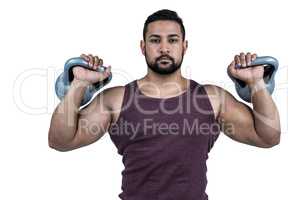 Muscular serious man lifting kettlebells