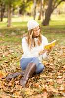 Smiling pretty woman reading a book in leaves