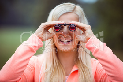 Happy blonde looking through binoculars