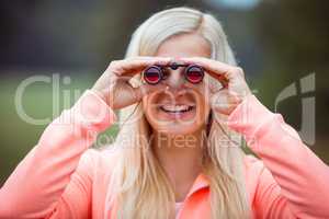 Happy blonde looking through binoculars