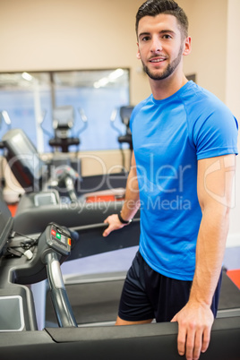 Smiling man standing on a treadmill