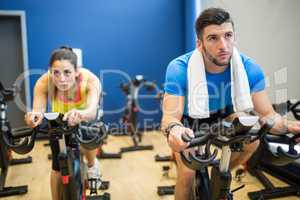 Focused couple using exercise bikes