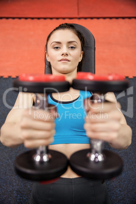 Smiling woman lifting dumbbells while lying down