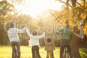 Rear view of a young family with arms raised on bike