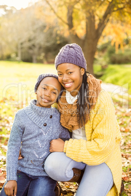 Young mother with her daughter sitting in leaves