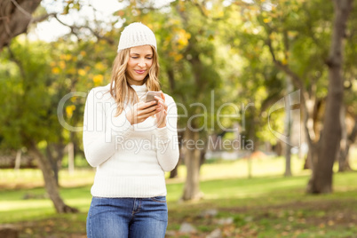 Smiling pretty woman texting with her smartphone