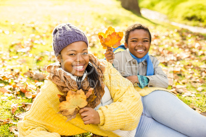 Young mother with her son sitting in leaves