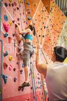 Instructor guiding woman on rock climbing wall