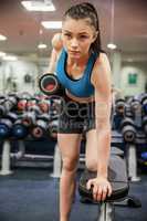 Focused woman lifting dumbbell weight in hand