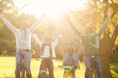 Young smiling family doing a bike ride with arms raised