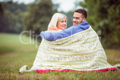 Happy couple sitting under blanket