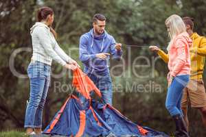 Happy friends setting up their tent