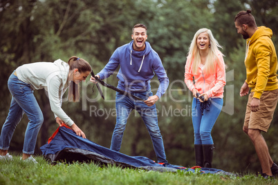 Happy friends setting up their tent