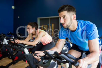 Focused man and woman on exercise bikes