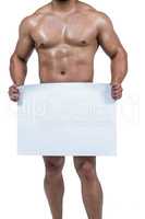 Muscular man covering crotch with poster