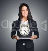 Business woman showing a metal alarm clock in front of him