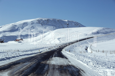Snowy and slippery road with volcanic mountains in wintertime