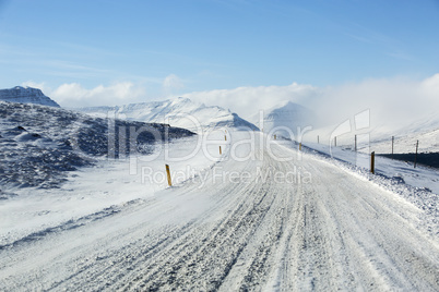 Snowy and icy road with volcanic mountains in wintertime