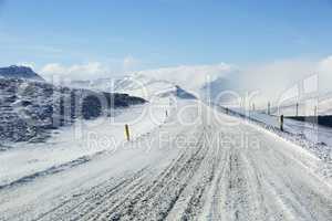 Snowy and icy road with volcanic mountains in wintertime