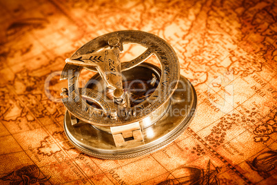 Vintage compass lies on an ancient world map.