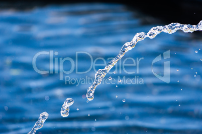 Close-up of water stream and droplets falling in arc