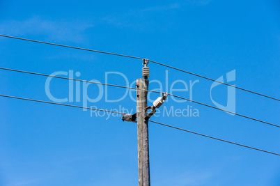 Old simple rural wood electrical pole on blue sky