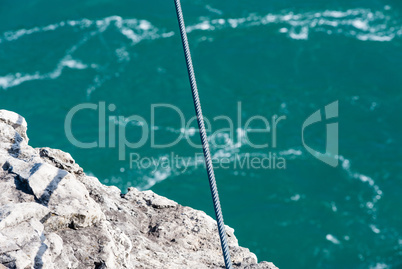 Tight steel cable over rock edge and river