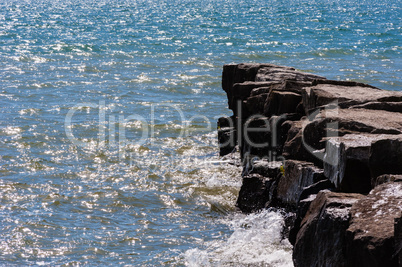 Waves on sunny day splashing against breakwall