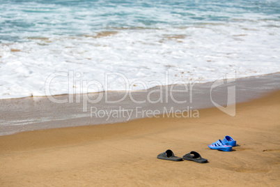 Women's and Men's Slippers on a Sandy Ocean Beach