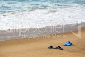 Women's and Men's Slippers on a Sandy Ocean Beach