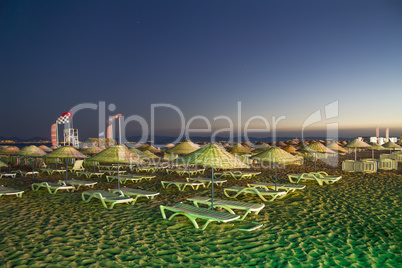 Beds and Straw Umbrellas On A Beach At Night