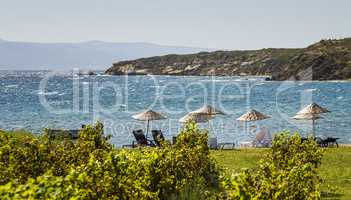Beds and Straw Umbrellas On A Beach By Grape Vines At Bozcaada,