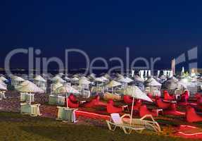 Beds and Straw Umbrellas On A Beach At Night
