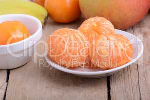 Bowls of slices mandarin with apple on rustic wooden background