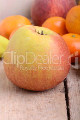 Bananas apple mandarin peach strawberry on wooden background as health food concept