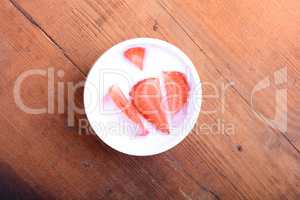 Slice of pie with strawberry on white plate, milk drink, wooden background. Top view