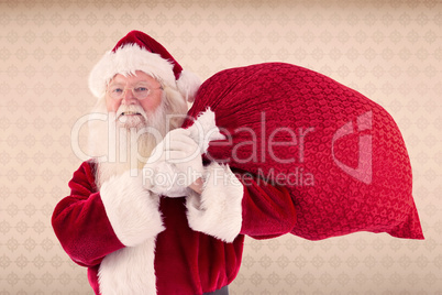 Composite image of santa carries his red bag and smiles