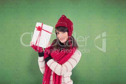 Composite image of smiling brunette showing a gift