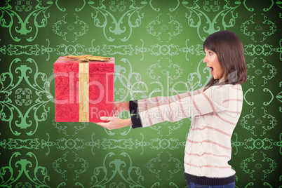 Composite image of surprised brunette holding a gift