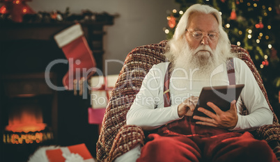 Santa claus using tablet on the armchair