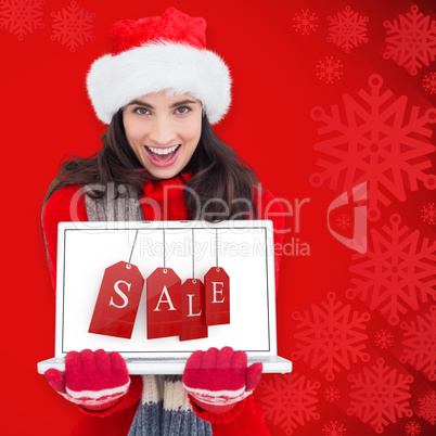 Composite image of festive brunette showing a laptop Composite image of festive brunette showing a laptop