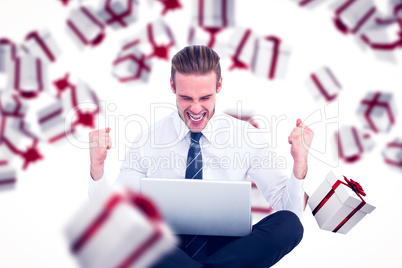 Composite image of businessman using laptop and cheering